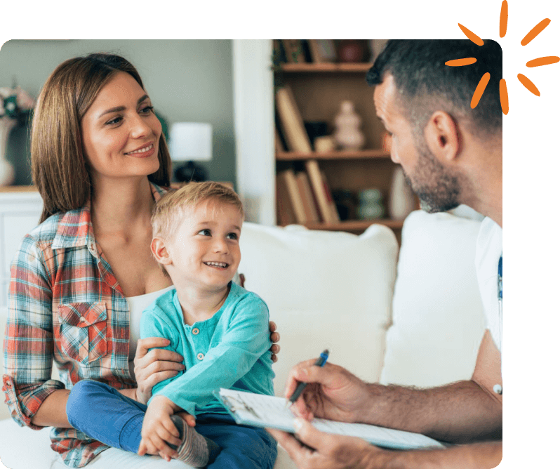 Parent and child smile while speaking with a pediatrician during a visit.