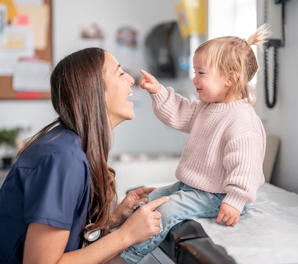 Smiling healthcare provider interacting with a young child.