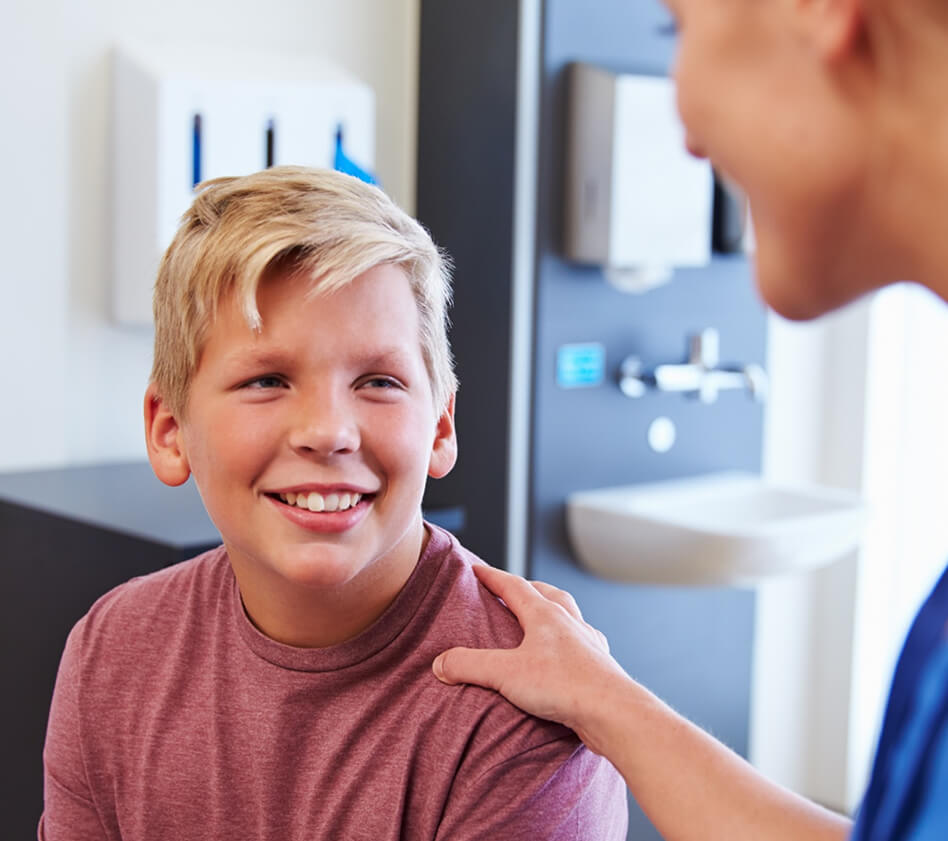 Smiling child talking with a healthcare provider during a medical visit.