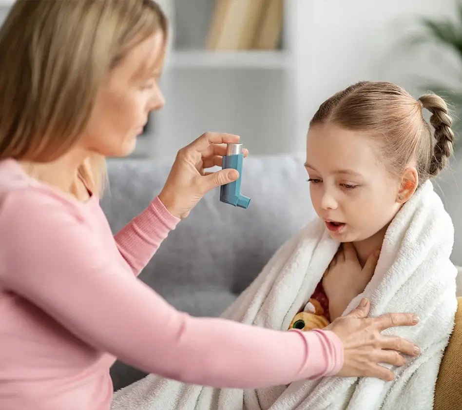 Parent helps a child use an asthma inhaler.