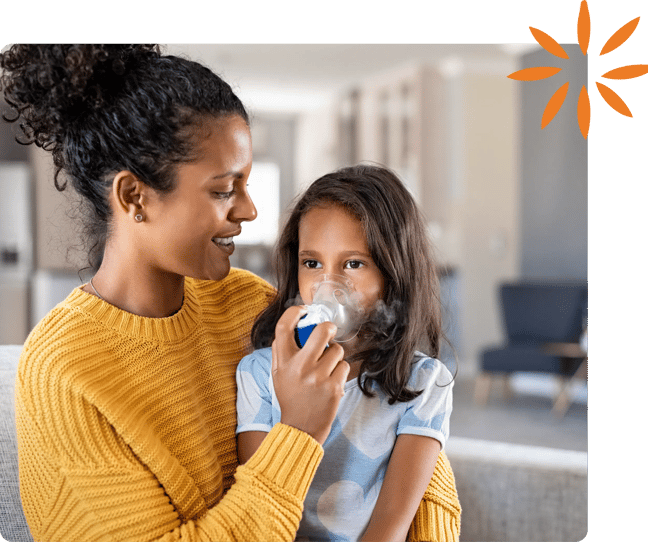 Parent helps a child use a nebulizer mask for an asthma treatment.