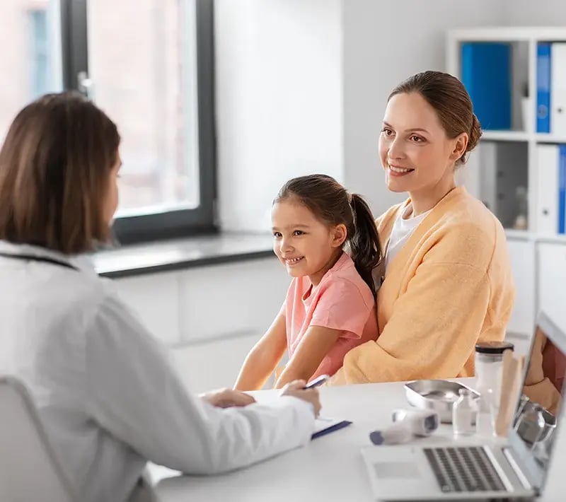 Mother and child meeting with a healthcare provider during a pediatric office visit.
