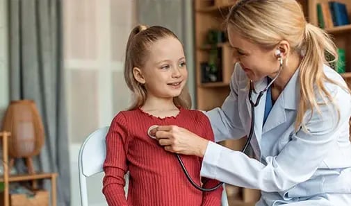 Pediatrician listens to a smiling child’s heartbeat during a routine checkup.