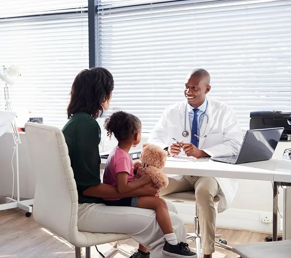 Pediatrician talks with a parent and child during an office visit.
