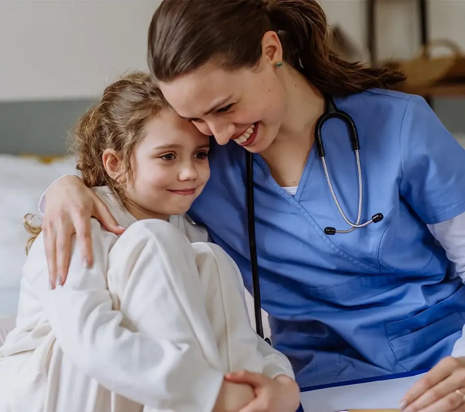 Healthcare provider comforts and hugs a young child during a sick visit.