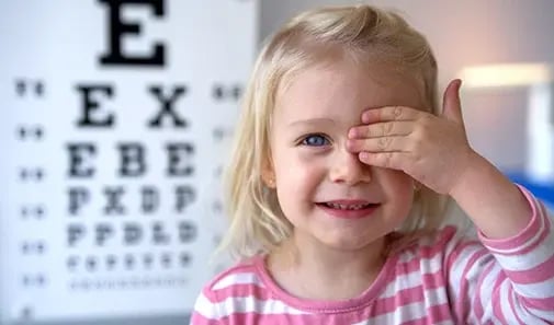 Toddler girl covering eye for vision test