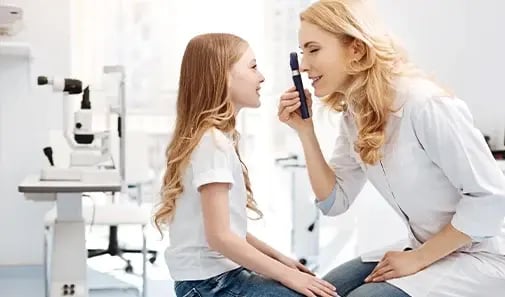 Optician examining eye of girl
