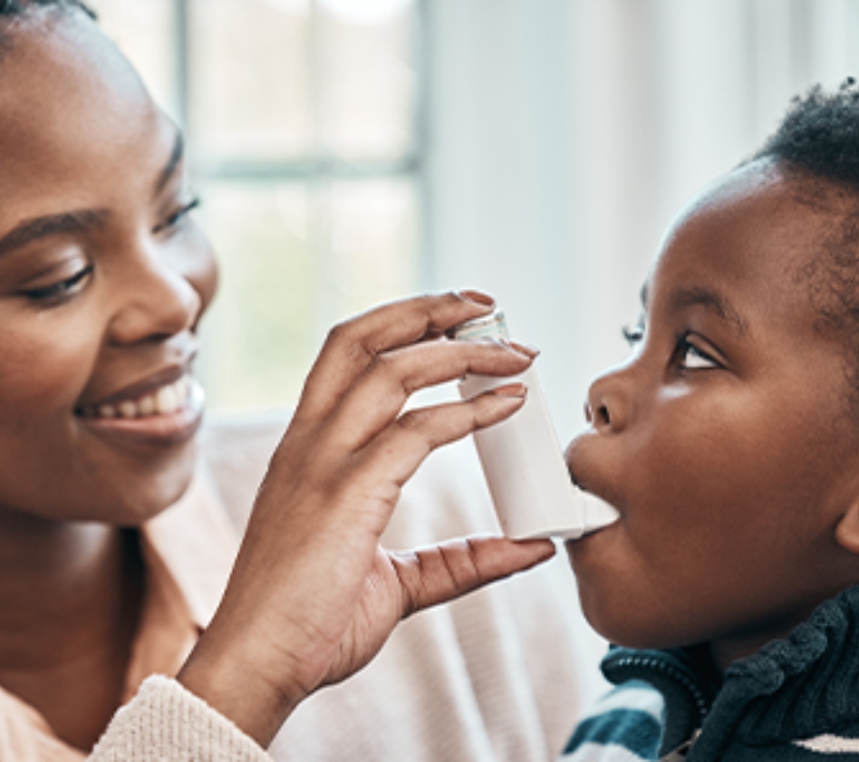 Parent helps a child use an asthma inhaler with a spacer.