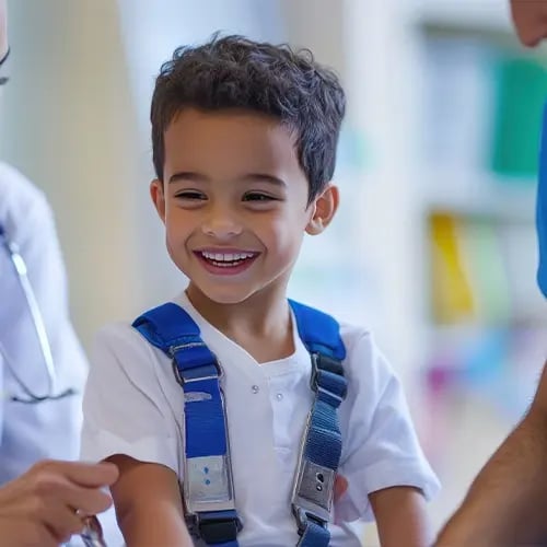 Smiling young child wears a safety harness during a sports physical exam.