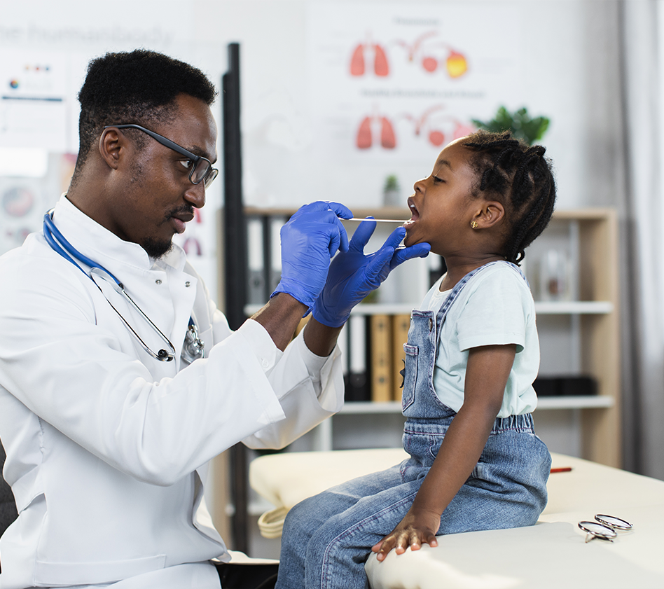 Pediatrician examines a young child’s throat during a wellness checkup.