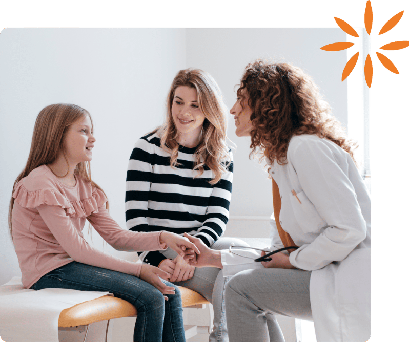 Pediatrician shakes hands with a young patient while a parent smiles nearby.